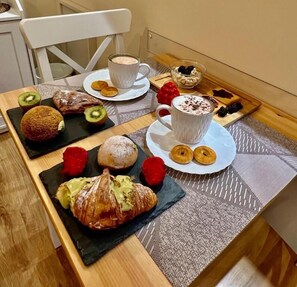 A breakfast setting with pastries, fruits, and a cup of coffee on a table. - Etna Vibes Home (Catania)