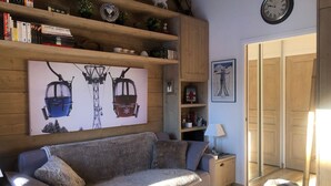 Un salon confortable avec un canapé, une table basse, une bibliothèque et une horloge murale.