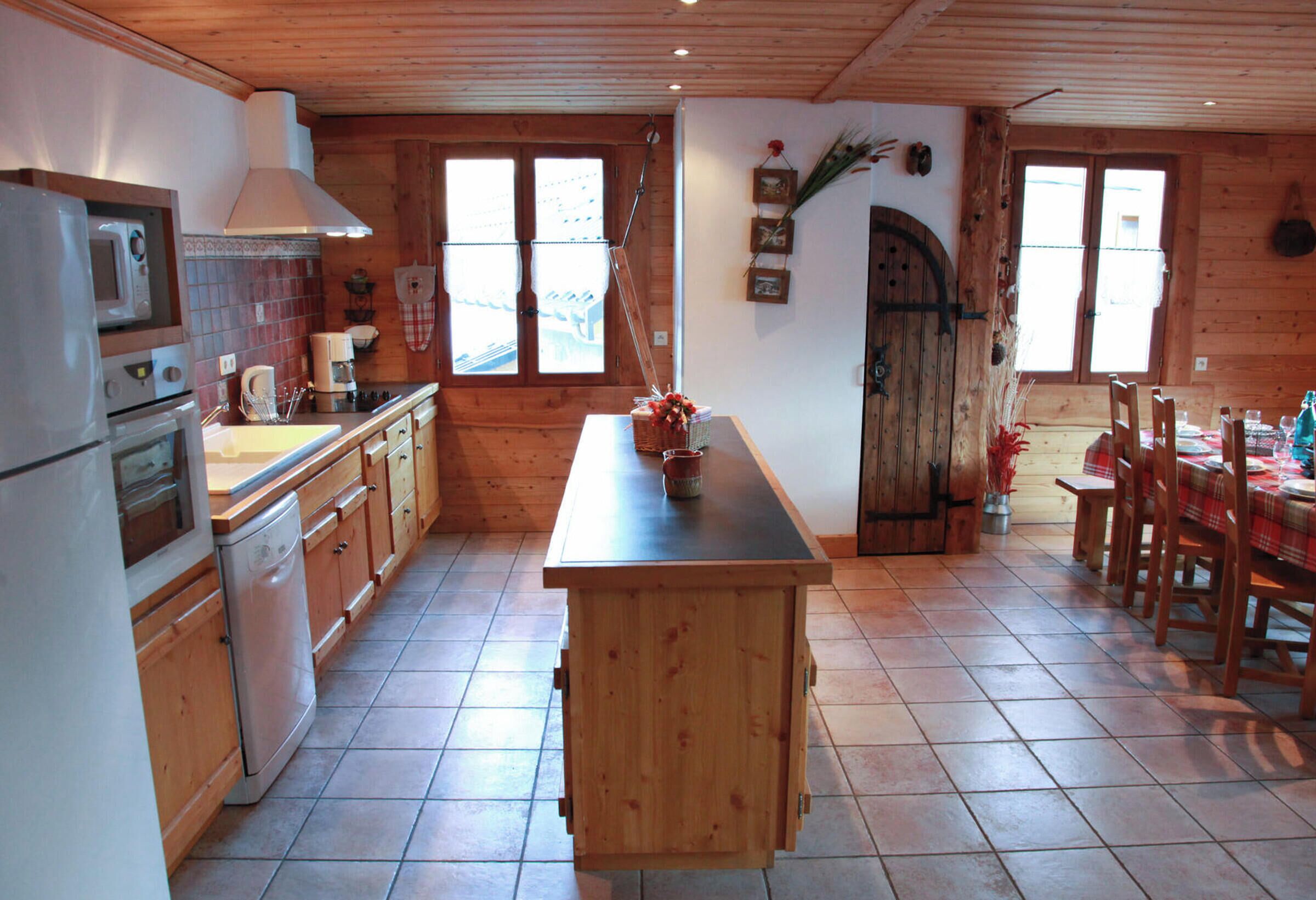 A kitchen with wooden cabinets, a central island, and a dining area with a table set for four.