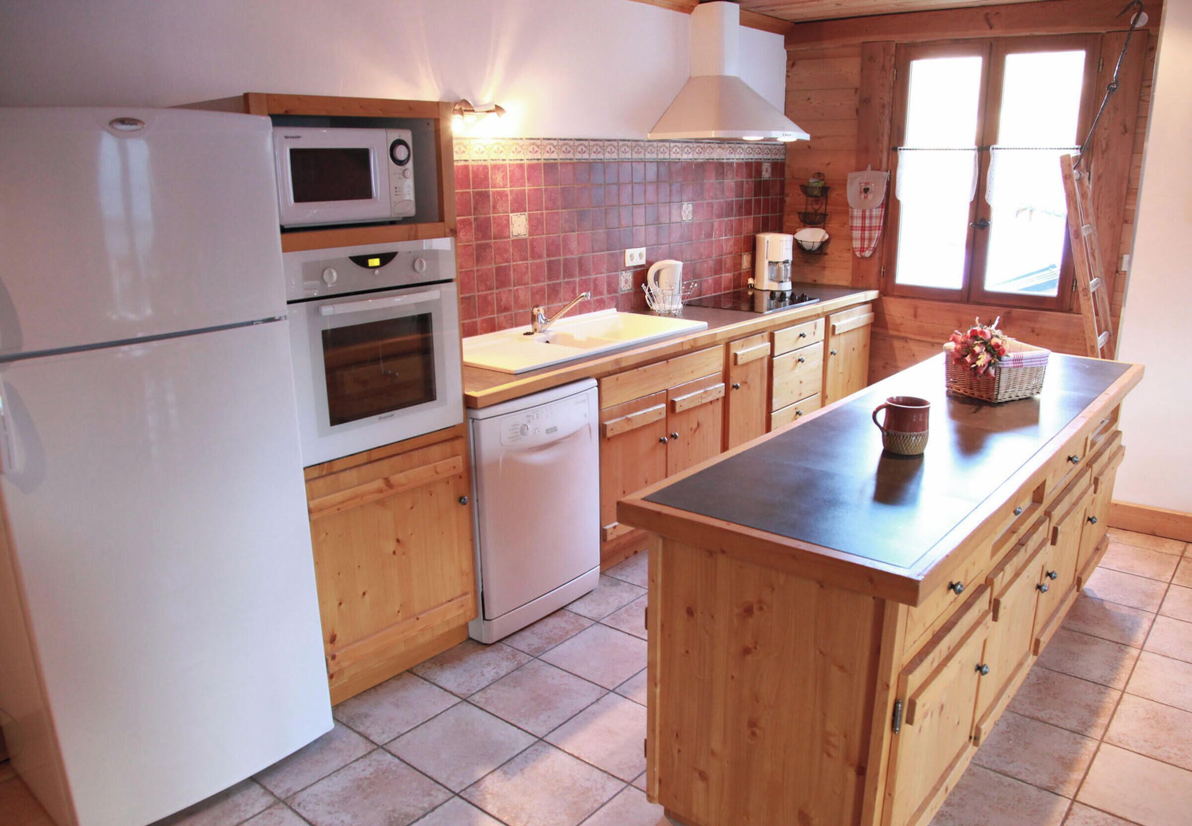 Eine Küche mit Holzausstattung, einer Mikrowelle, einem Backofen, einem Geschirrspüler, einer Spüle und einer Kaffeemaschine.