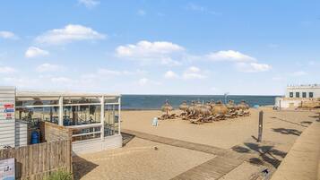 Un restaurante en la playa con terraza y vistas al mar.