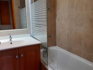 A bathroom with a white bathtub, a sink, and a mirror. - 2-room apartment, parking - 4 guests (Valloire)
