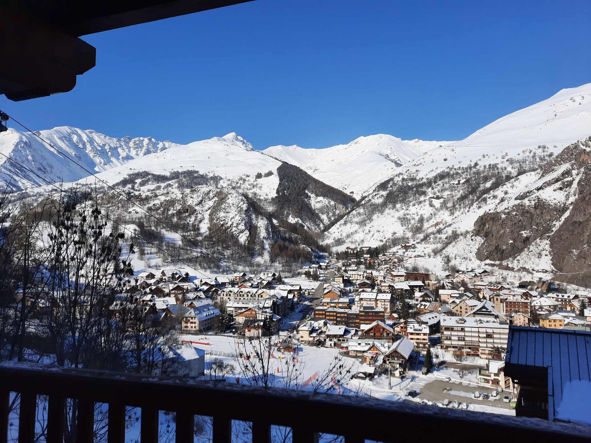 Une ville de montagne enneigée, avec des bâtiments et un ciel bleu dégagé.
