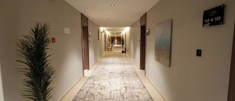 Un pasillo de hotel con alfombra estampada, una planta en maceta y un cartel que indica las habitaciones 110 y 109.