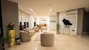A modern living room with sofas, a coffee bar, and a large black wall art piece.