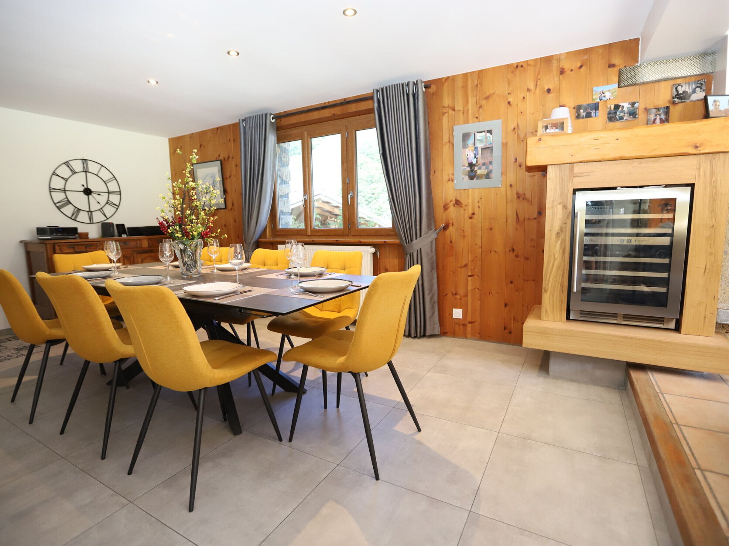A dining area with a wooden wall, a clock, and a fireplace.