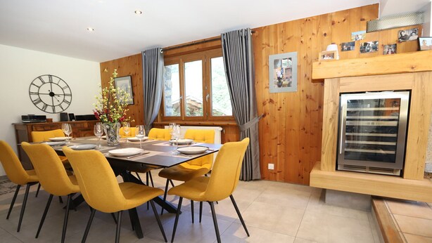 Un coin repas avec un mur en bois, une horloge et une cheminée.