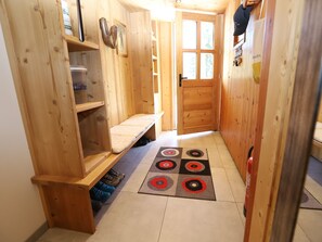 A wooden interior with a bench, shelves, a door, and a patterned rug.