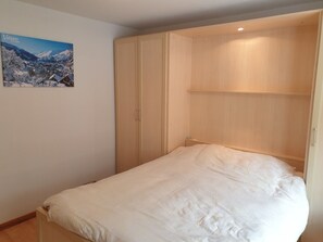 Ein Schlafzimmer mit Bett, Kleiderschrank und einem Bild an der Wand.