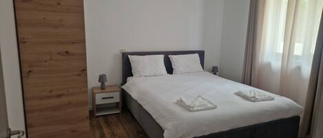 Un dormitorio con cama, mesita de noche, lámpara y puerta de madera.
