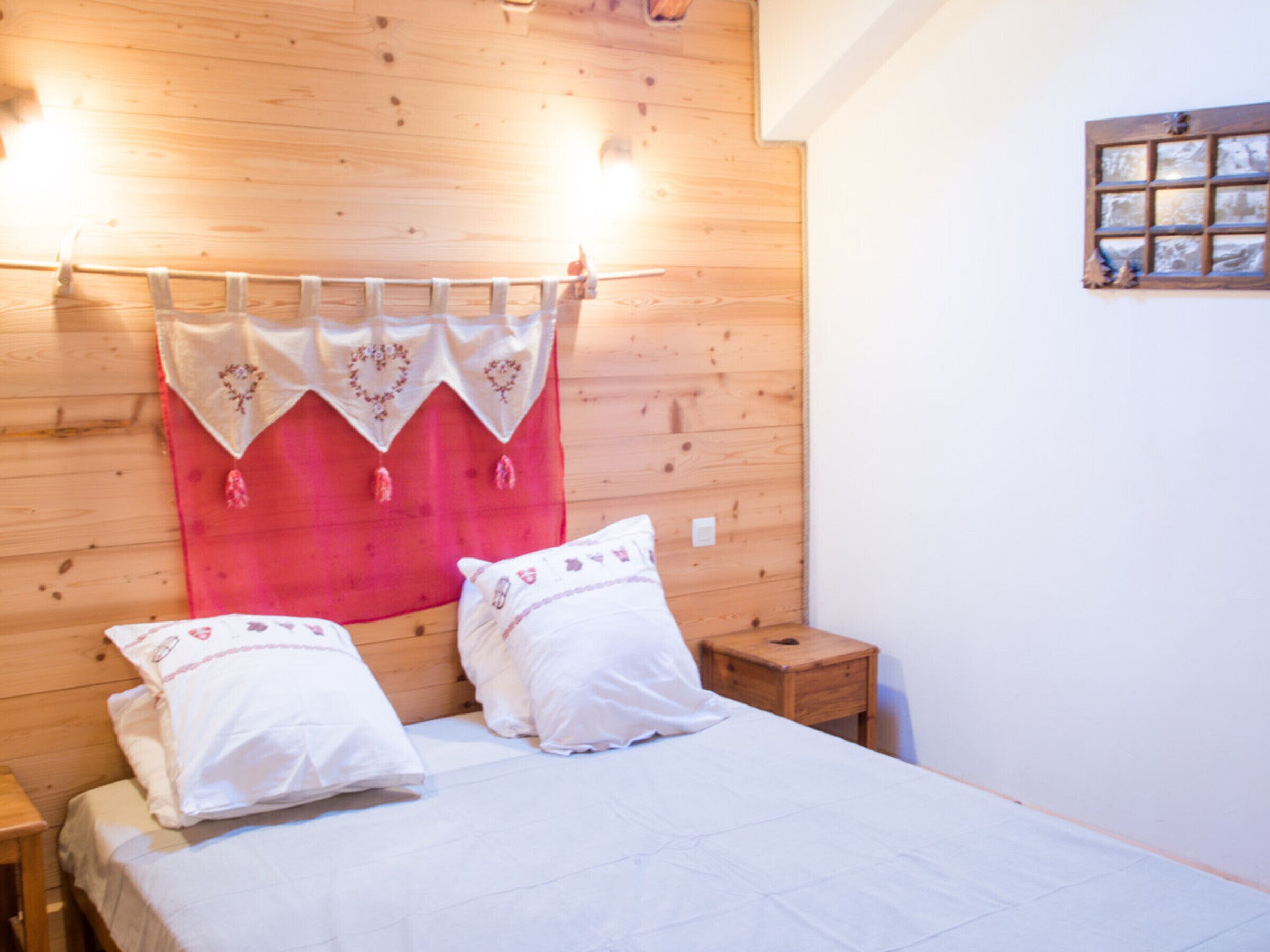 Un dormitorio con cabecera de madera, una cama con ropa de cama blanca y una mesita de noche.
