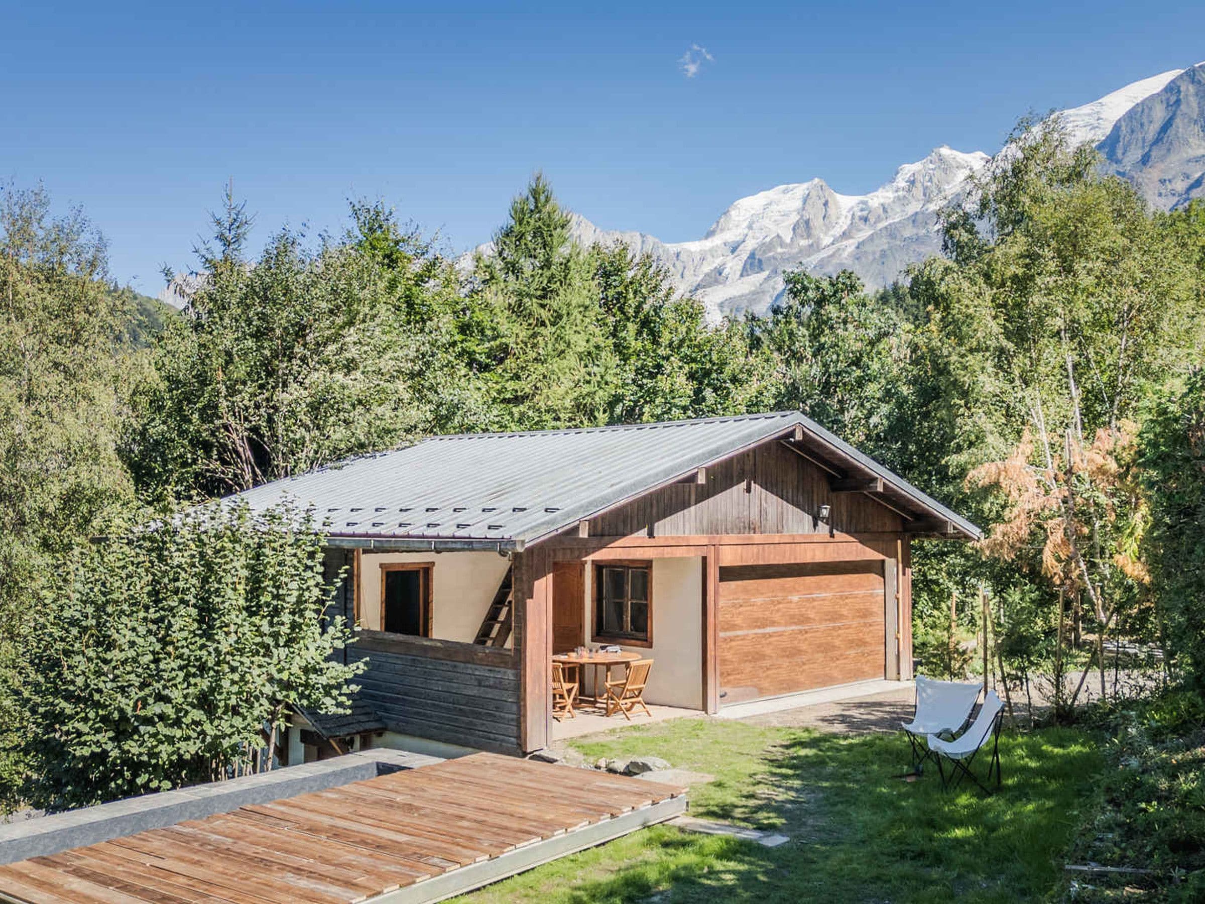 Une cabane avec une façade en bois, une terrasse et une vue sur les montagnes.