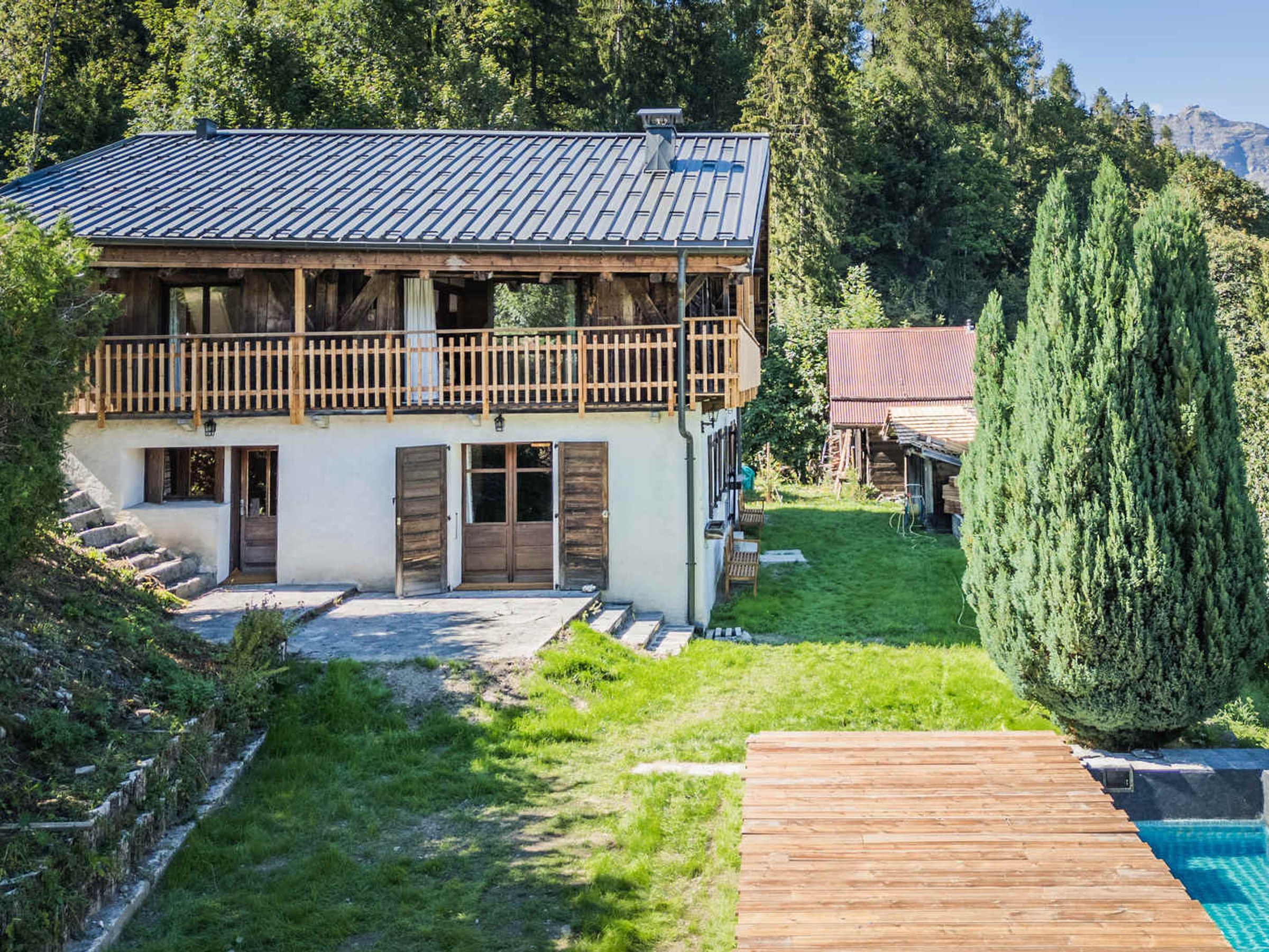 A two-story chalet with a balcony, a swimming pool, and a well-maintained garden.