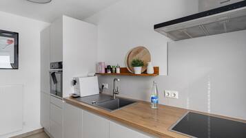 Eine moderne Küche mit weißen Schränken, einer Holzarbeitsplatte, einem eingebauten Backofen, einer Spüle und einer Siemens-Dunstabzugshaube.