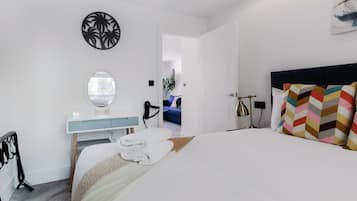 Une chambre d’hôtel moderne équipée d’un lit, d’une coiffeuse avec miroir, d’un sèche-cheveux et donnant sur le couloir.
