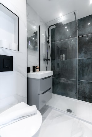 A modern bathroom with a glass-enclosed shower, a white sink, and a mirror.