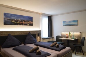 Een hotelkamer met twee bedden, een bureau, een stoel en uitzicht op een stadsbeeld.