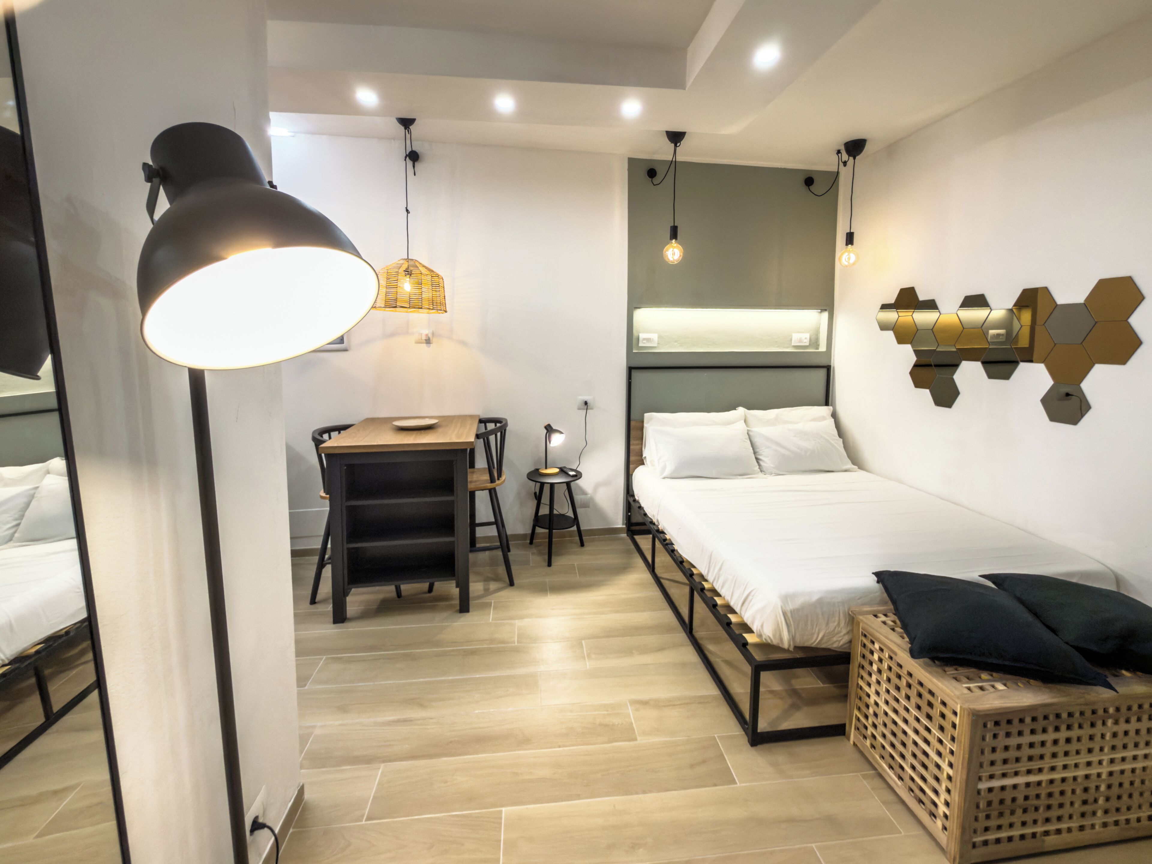 Ein modernes Schlafzimmer mit Bett, Nachttisch, Lampe und Wandleuchte.
