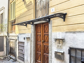 A building with a wooden door, a metal awning, and a number '6' on the wall. - LikeYourHome (Vercelli)