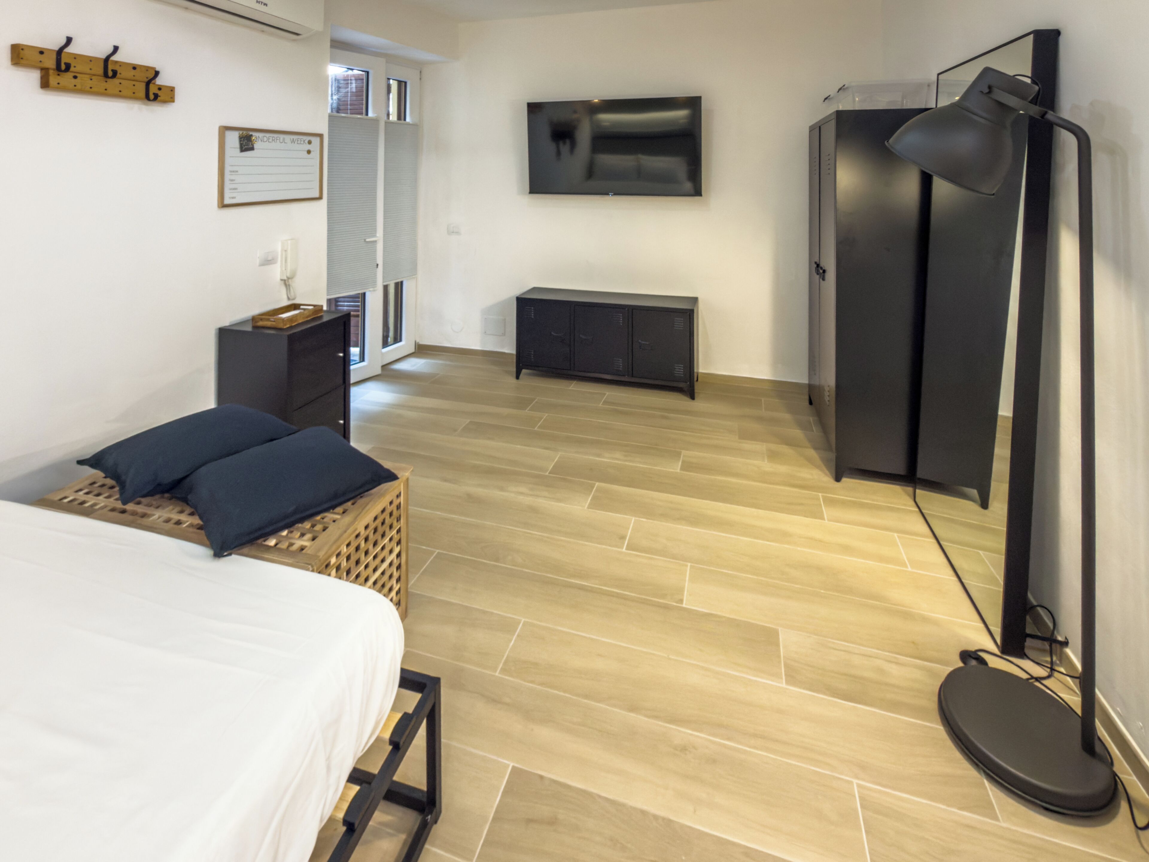 Une chambre à coucher comprenant un lit, une table de chevet, une armoire, un téléviseur et un bureau avec une chaise.