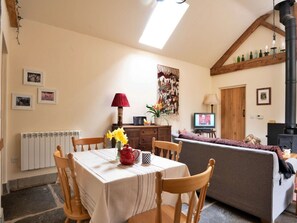 A cozy living room with a dining table, chairs, a sofa, a fireplace, and a television. - Sea View Carbis Bay House for 6 (Llandrindod Wells)