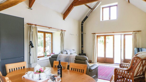 A cozy living room with a fireplace, a dining table set for tea, and a comfortable seating area. - May Cottage (Haverfordwest)
