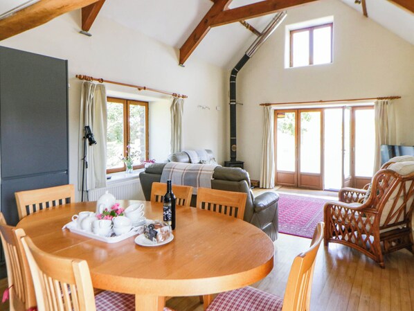 A cozy living room with a fireplace, a dining table set for tea, and a comfortable seating area. - May Cottage (Haverfordwest)