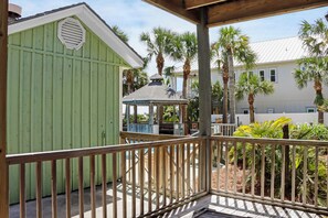 A wooden deck with a gazebo, a green building, and palm trees. - 🌴Hidden Palms | Steps to Beach | Private Pool | Tiki Bar | 5BR🌴 (Indian Pass)
