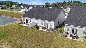 A residential area with multiple houses, a small body of water, and a well-maintained lawn. - Osprey Cove | Townhouse in Ocean Isle Beach (OCEAN ISL BCH)