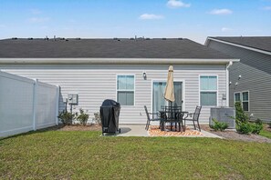 A residential building with a covered patio, a grill, and a fenced yard. - Osprey Cove | Townhouse in Ocean Isle Beach (OCEAN ISL BCH)