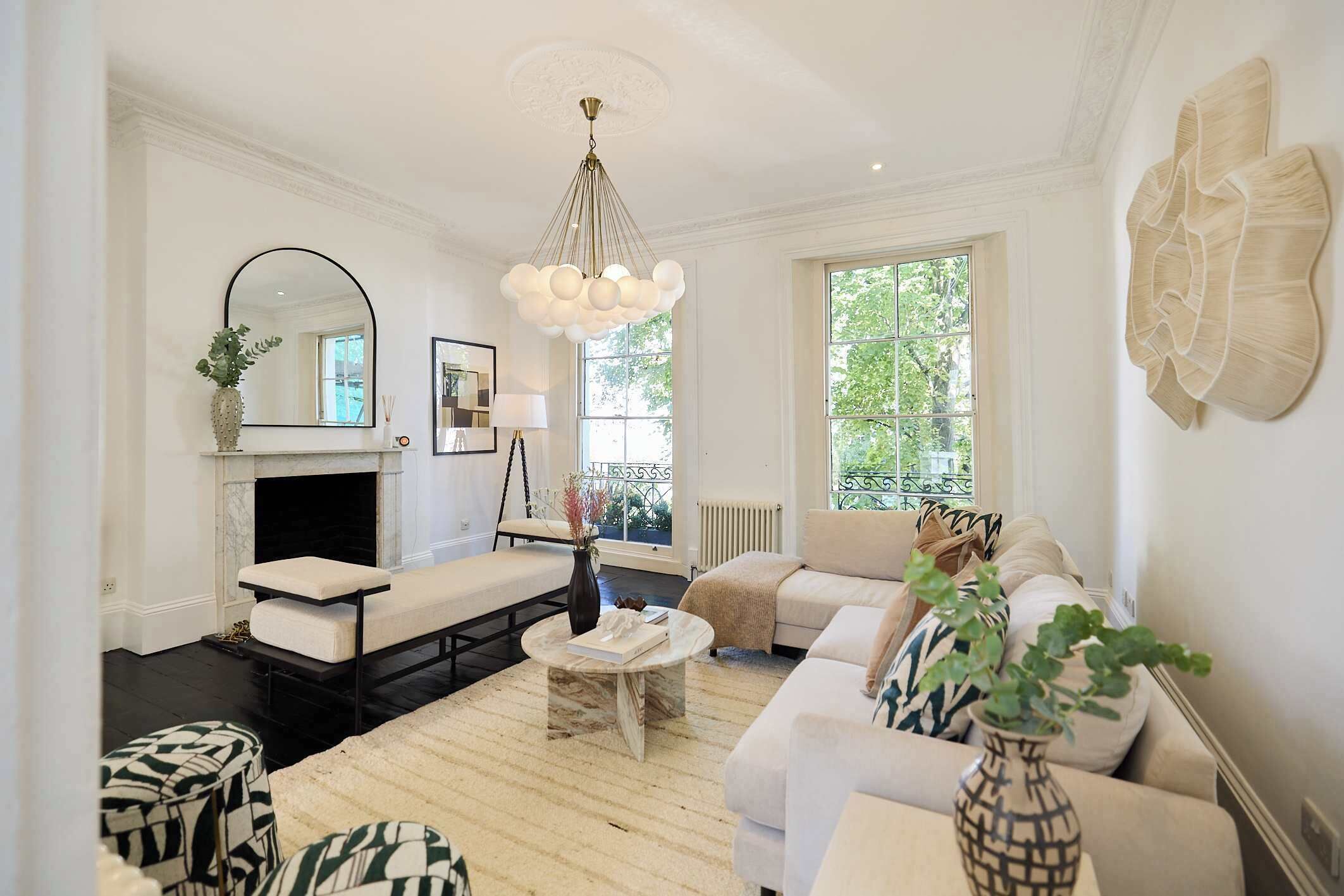 Un salon avec une cheminée, un canapé, une table basse et une grande fenêtre.