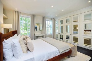 Ein Schlafzimmer mit einem großen Bett, einem Nachttisch, einem Spiegel und Einbauschränken.