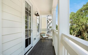 Une véranda couverte avec un plancher en bois, une chaise et une fenêtre.