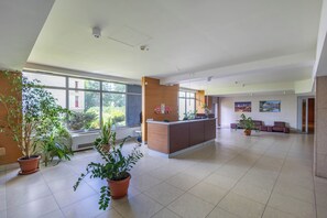 A spacious lobby with a reception desk, large windows, and potted plants. - Dickensa Apartment (Warszawa)