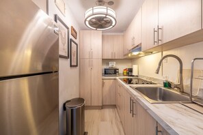 A modern kitchen with stainless steel appliances, wooden cabinets, and a built-in microwave. - Vicky's Beach Front Oasis (Luquillo)