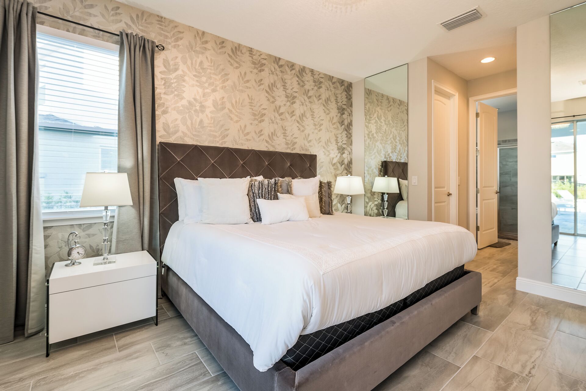 Une chambre moderne avec un grand lit, deux tables de chevet et une vue sur l’extérieur.
