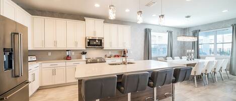 A modern kitchen with white cabinets, stainless steel appliances, and a central island with bar stools.