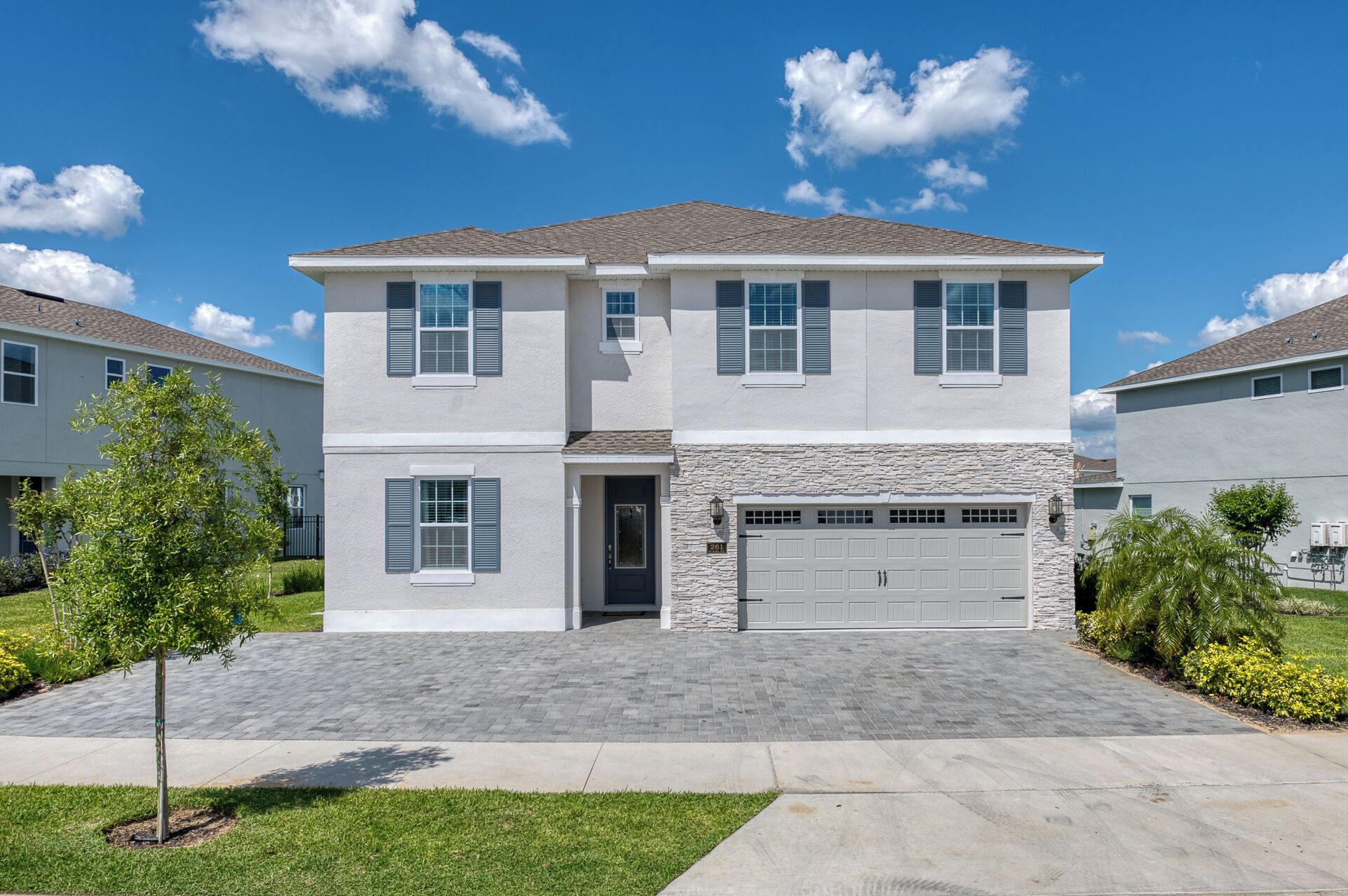 A two-story residential house with a stone facade, a garage, and a well-maintained lawn.