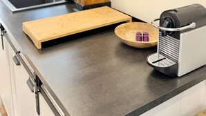 Un comptoir de cuisine avec une machine à café, une planche à découper et un saladier en bois.