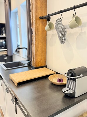Eine Küchenarbeitsplatte mit einer Kaffeemaschine, einem Schneidebrett und einer Holtschüssel.