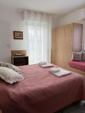 A bedroom with a bed, a wardrobe, and a window with curtains. - Pirandello Rooms (Verona)