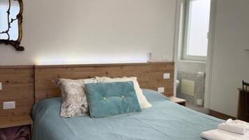 Une chambre à coucher avec un lit, des oreillers, une table de chevet et une fenêtre.
