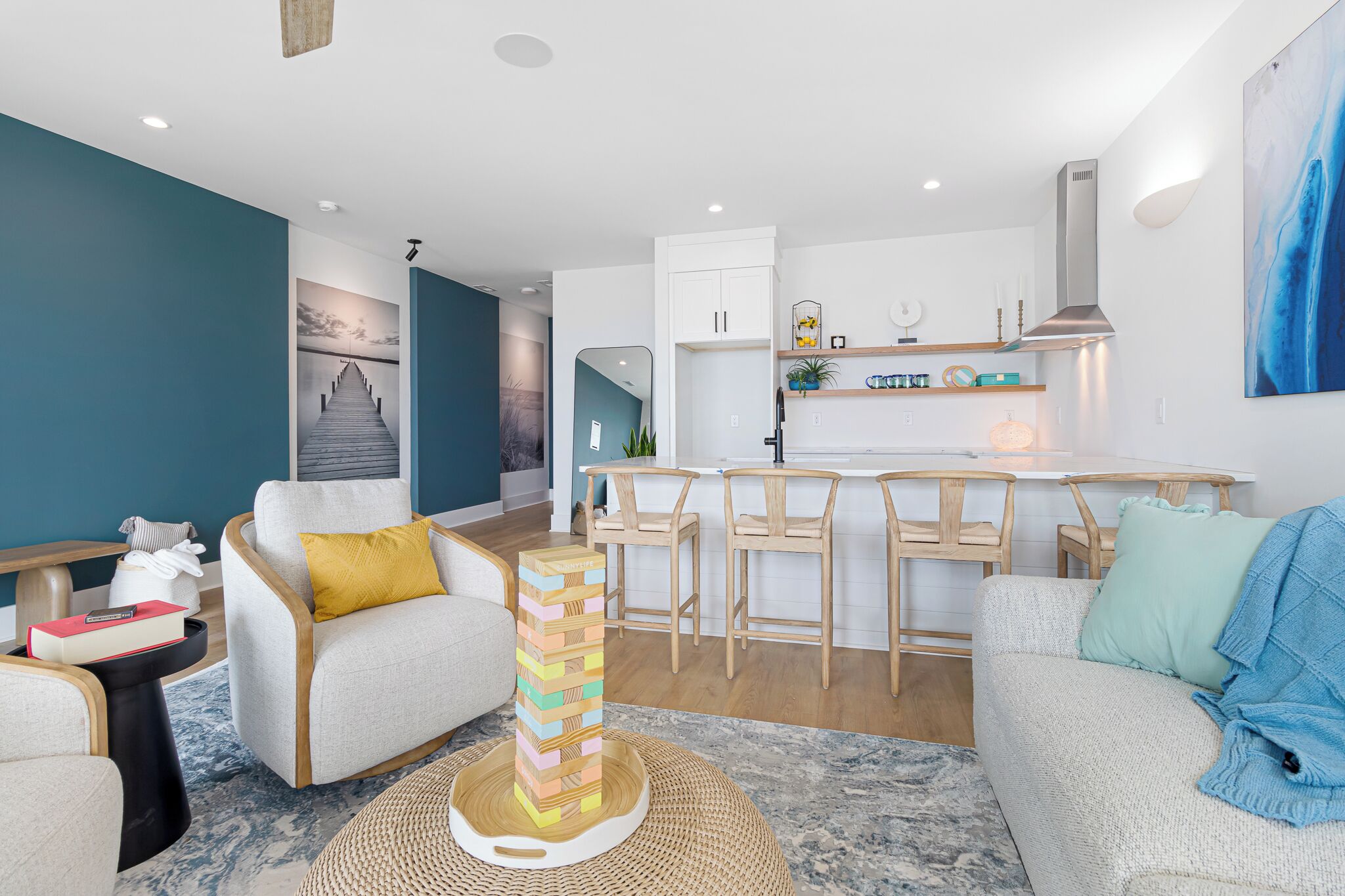 A modern living room with a sofa, a coffee table with a jigsaw puzzle, a kitchen area with bar stools, and a dining table.