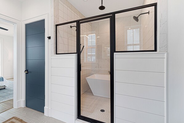 A modern bathroom with a glass shower enclosure, a bathtub, and a toilet. - Sea Spray East | Oceanfront Duplex with Private Pool + Elevator (Emerald Isle)
