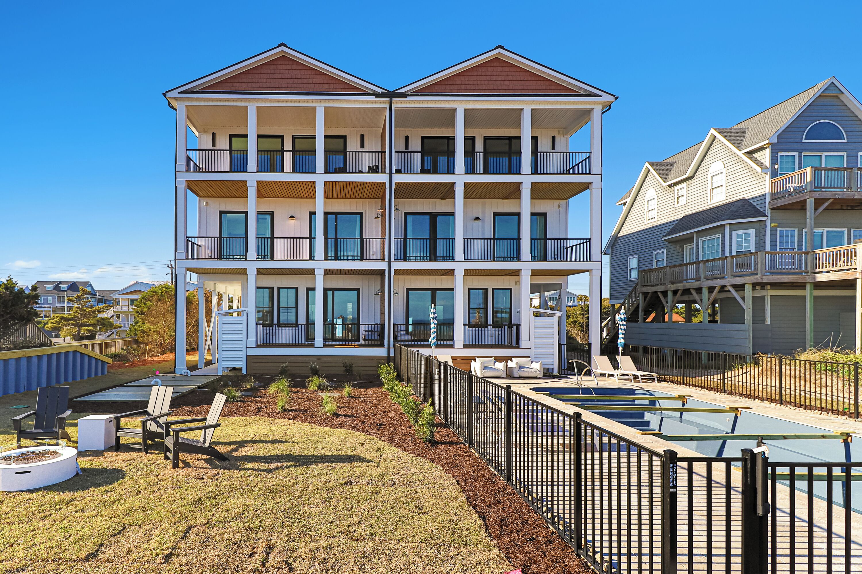 A multi-story building with balconies, a swimming pool, and outdoor seating.