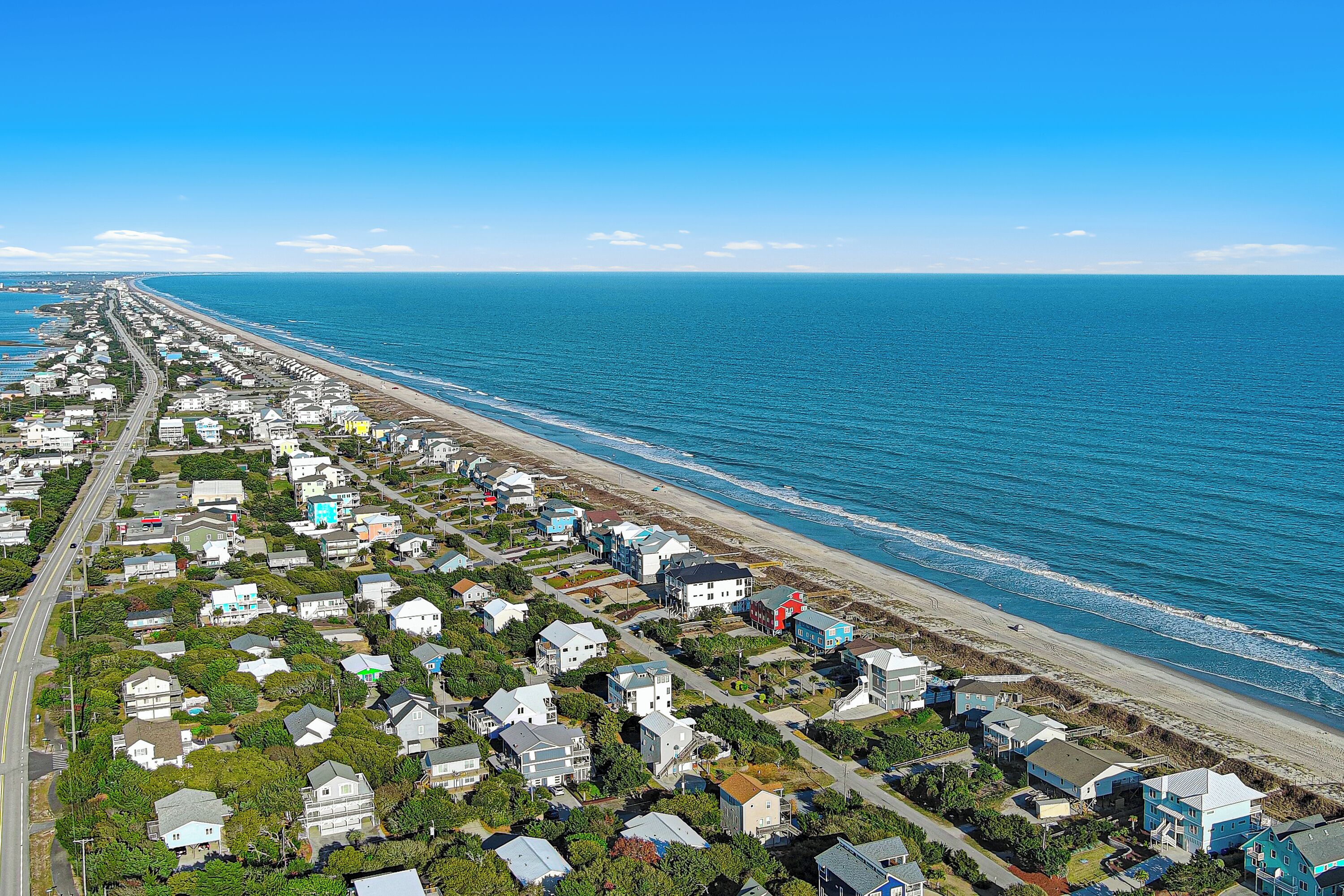A coastal residential area with houses along the beachfront and a road parallel to the beach.