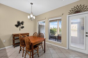 A dining area with a wooden table and chairs, a chandelier, and a decorative wall piece.