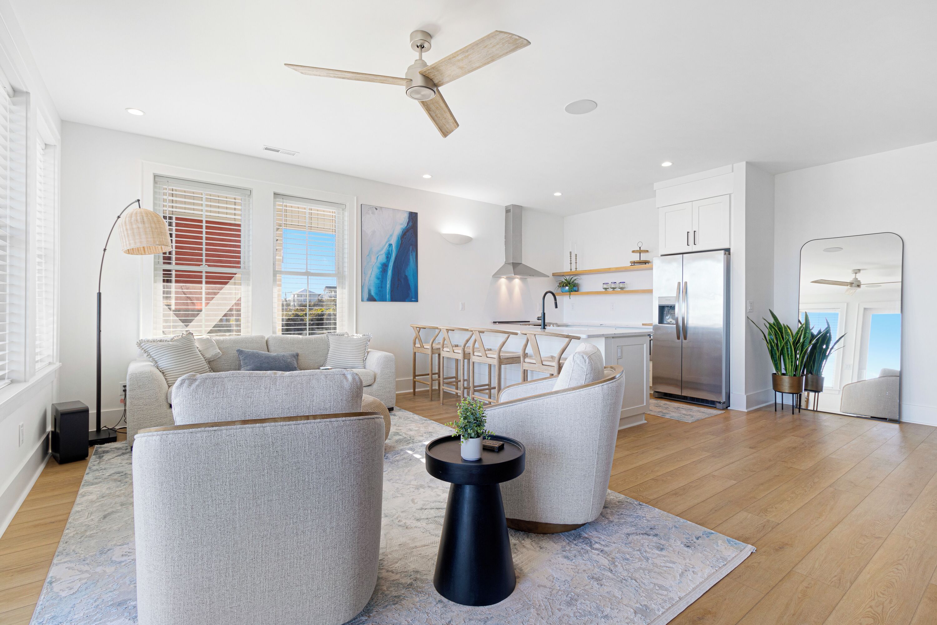A modern living room with a sofa, armchairs, a coffee table, and a ceiling fan.