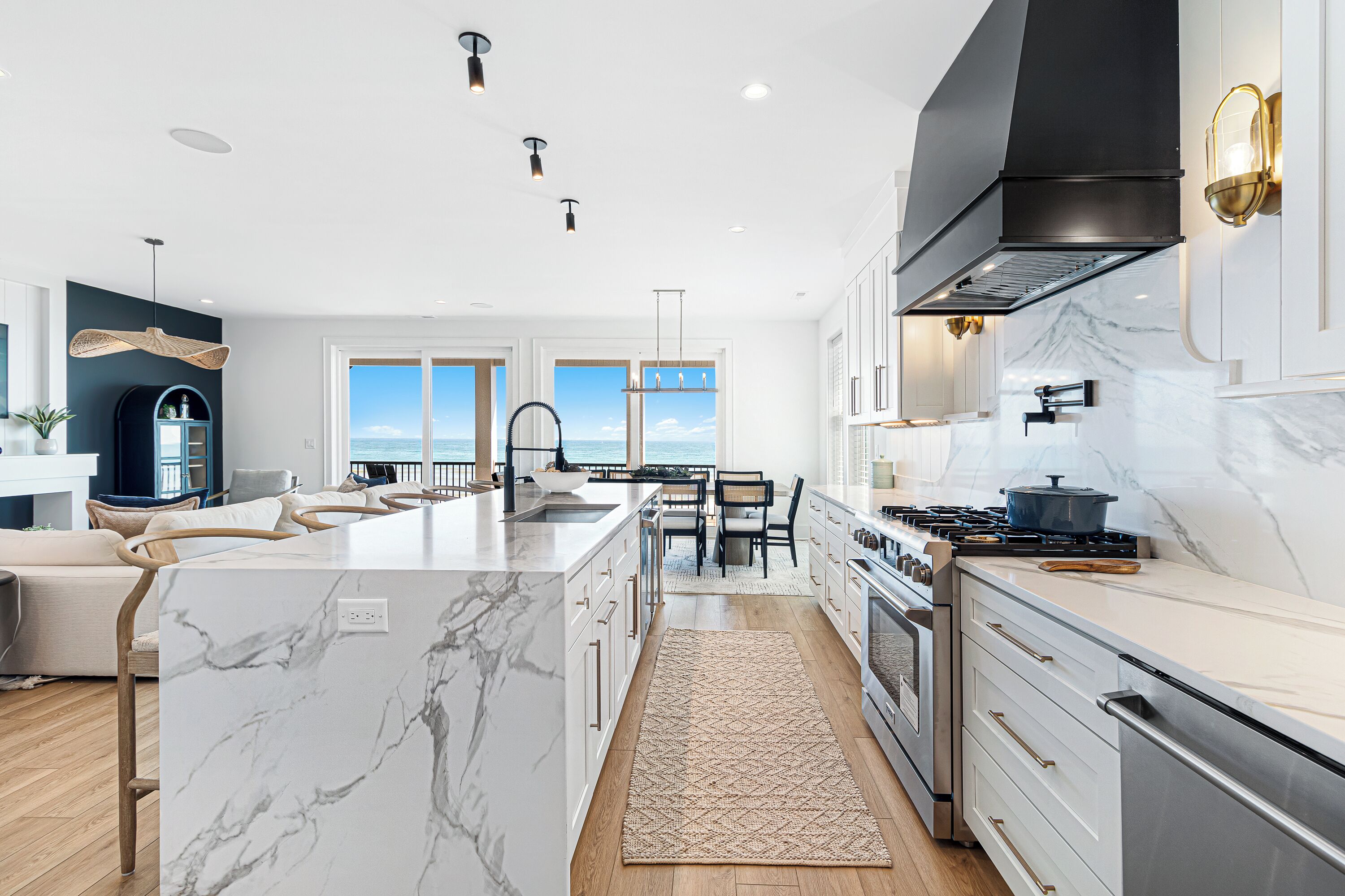 A modern kitchen with a large island, stainless steel appliances, and a view to the outside.