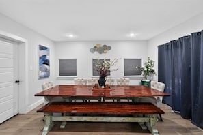 A dining room with a large wooden table, six chairs, a vase with flowers, and decorative wall art. - Firepit Family Basecamp Euless 3 Bedroom Home (Euless)